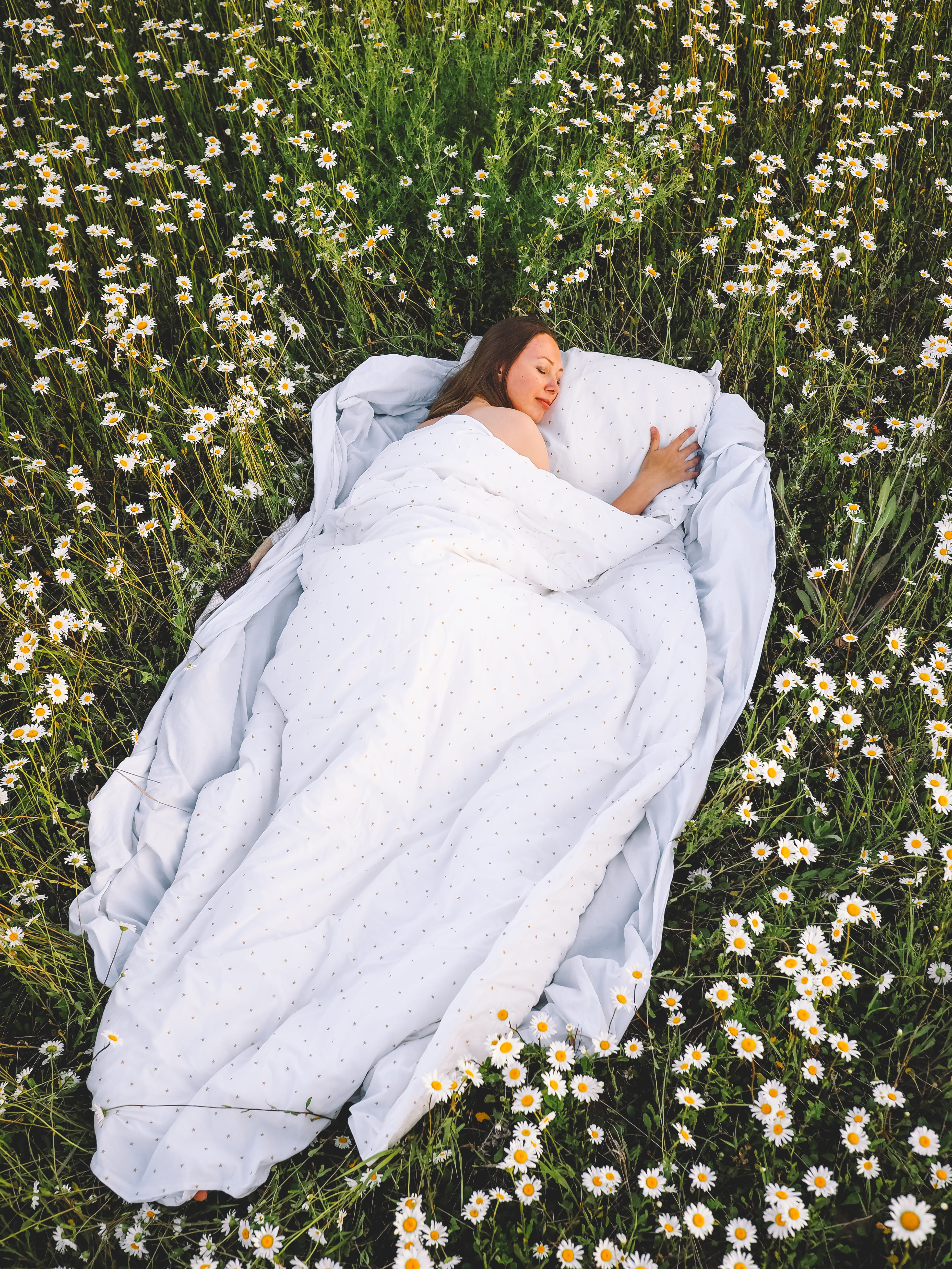 Femme dormant paisiblement dans un champ fleuri avec une couette légère d'été