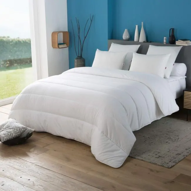 Couette Dodo Tempérée légère et respirante sur un lit blanc — modèle fabriqué en France