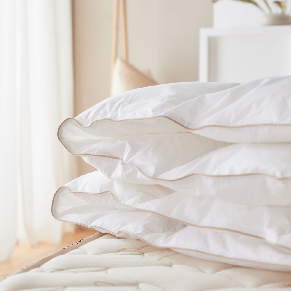 Couette en duvet et plume sur un grand lit, vue de dessus montrant les différentes tailles disponibles