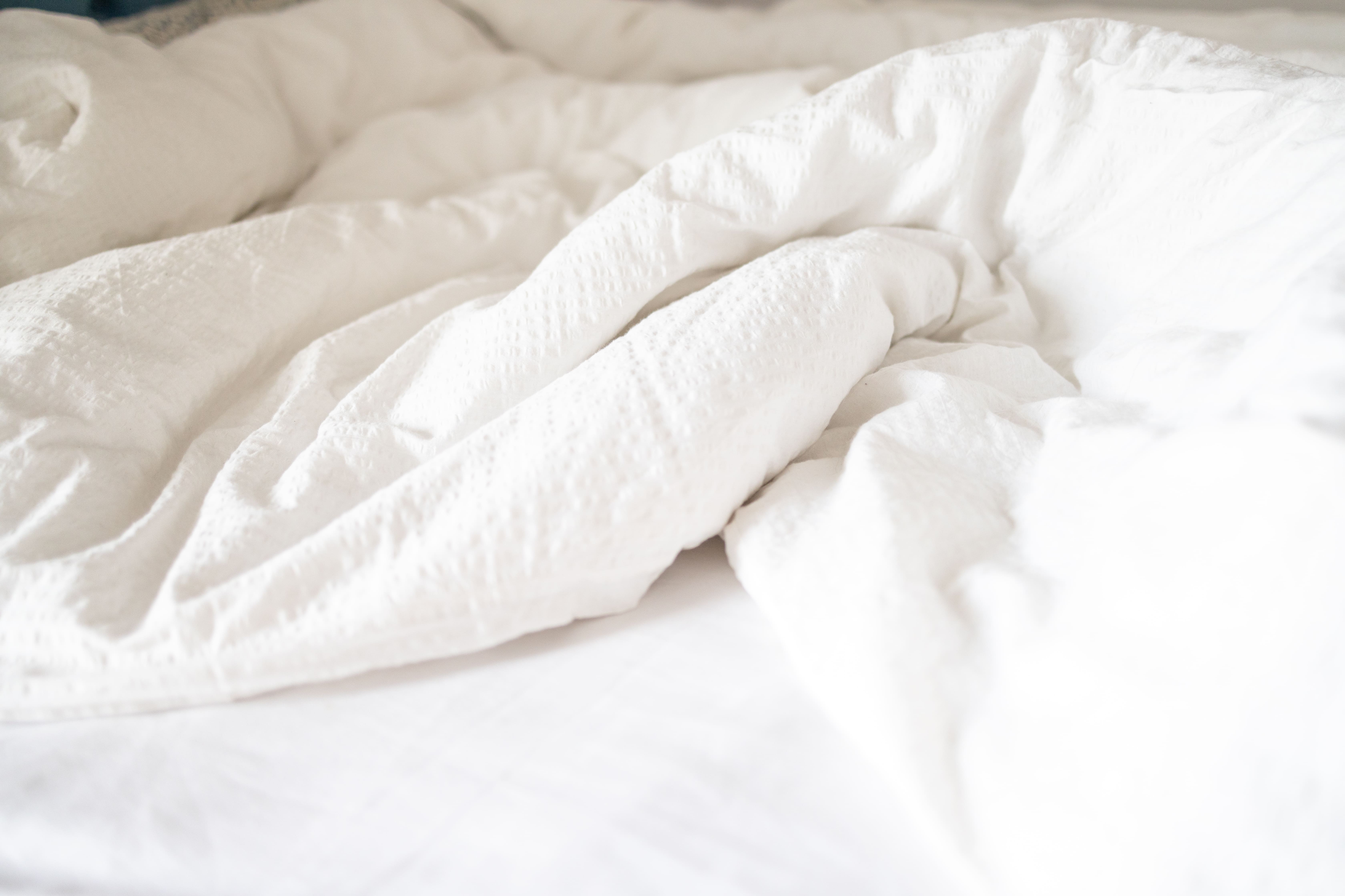 Literie défaite avec couette et oreiller sur un lit — hygiène et entretien